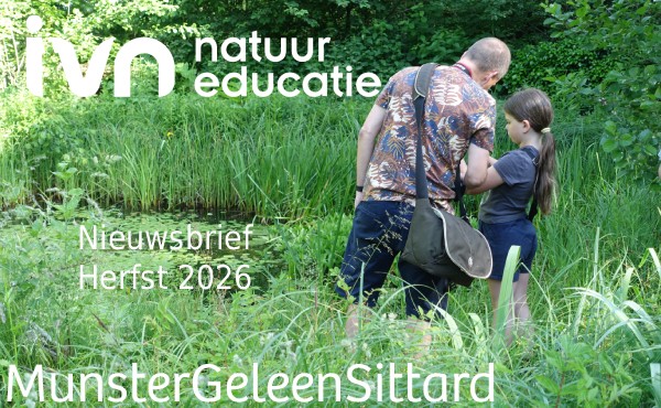 Man legt zijn dochter uit wat in de vijver in de heemtuin zit.